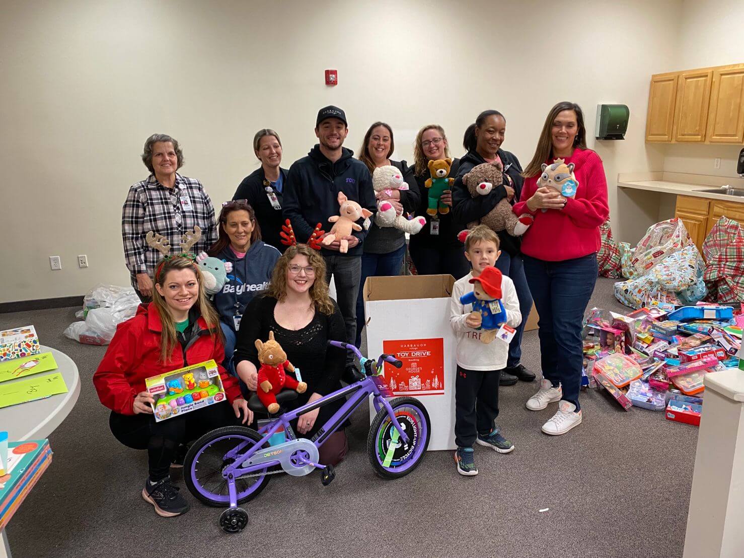 TCC team smiling with toys for TCC and Harbaugh Village’s Holiday Joy Raiser