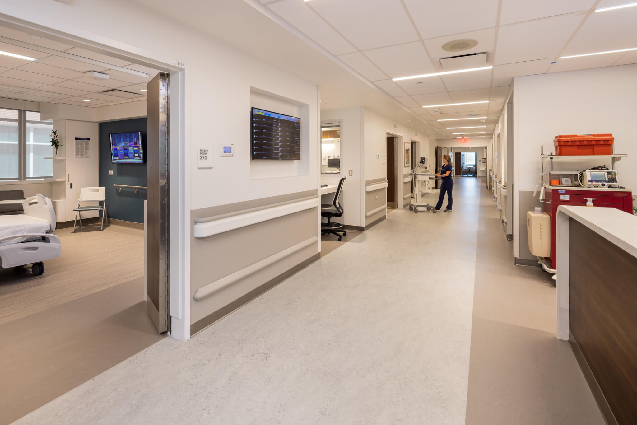 A hospital hallway with a reception desk and chairs for patients and visitors.